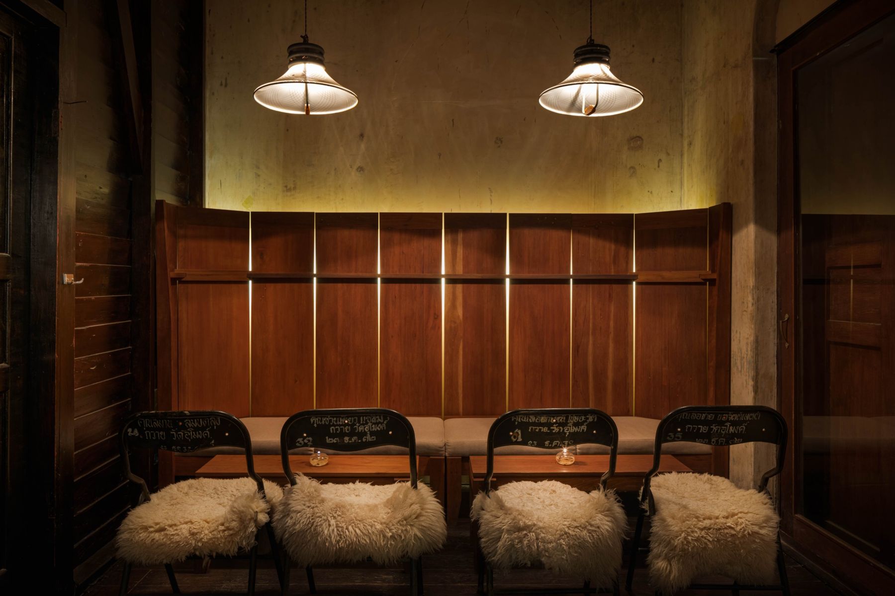 Teak-panelled lounge with pendant lamps and sheepskin chairs